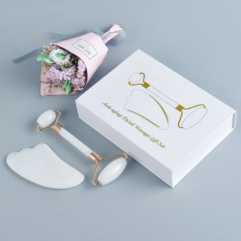 White jade facial roller and gua sha board set on a neutral background.