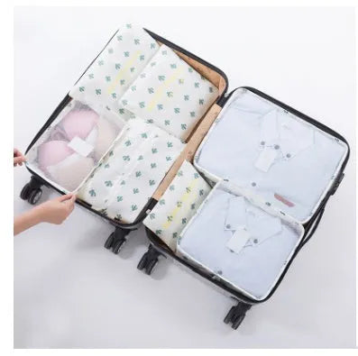 Six-pack of waterproof nylon packing cubes and flat bags in assorted sizes on a light background