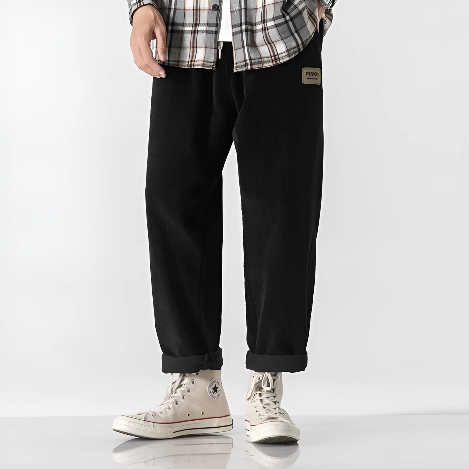 Men's loose straight corduroy sports trousers in black, front view, lying flat, showing waist and leg cut