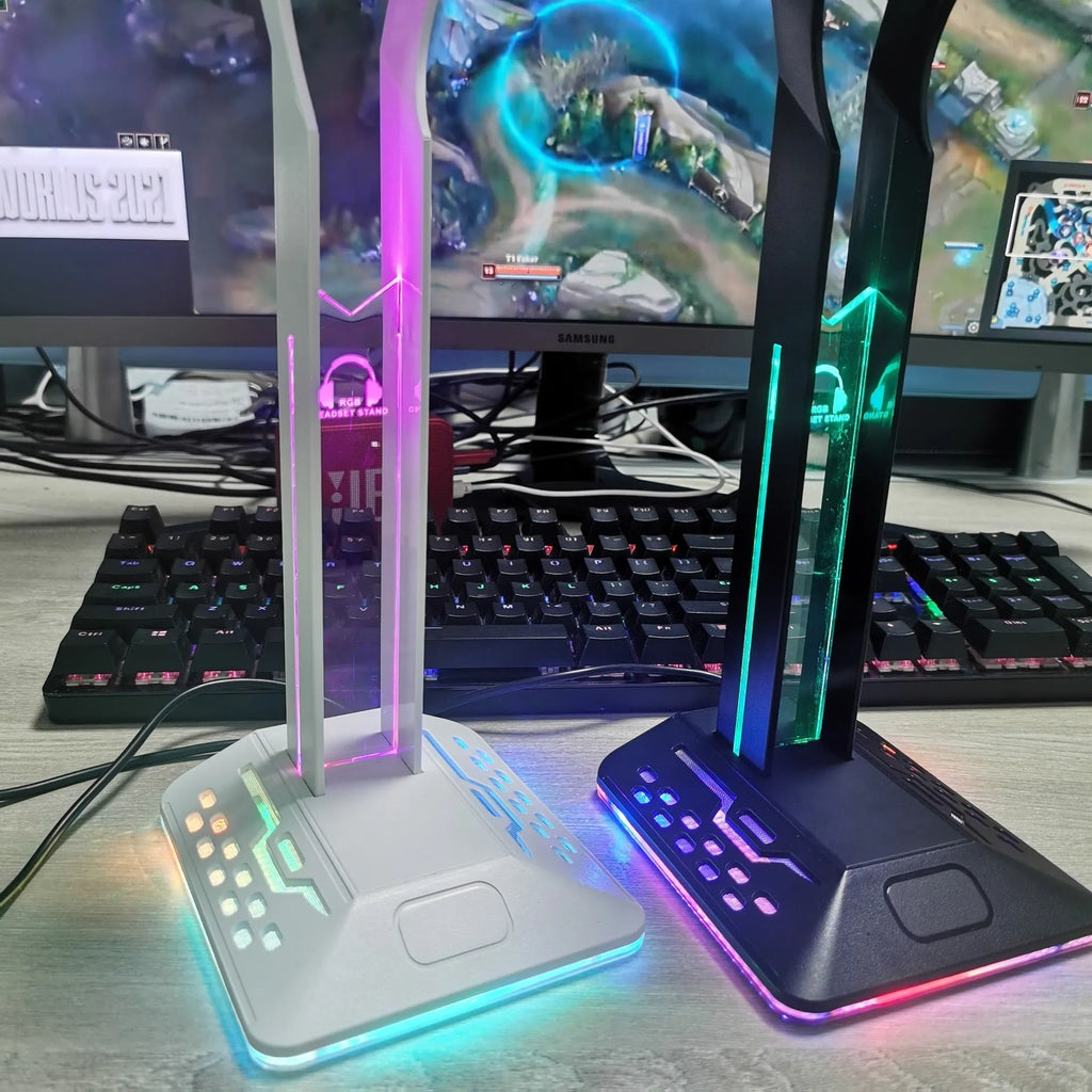 RGB colour changing headphone stand with dual USB ports on a desk next to a gaming headset.