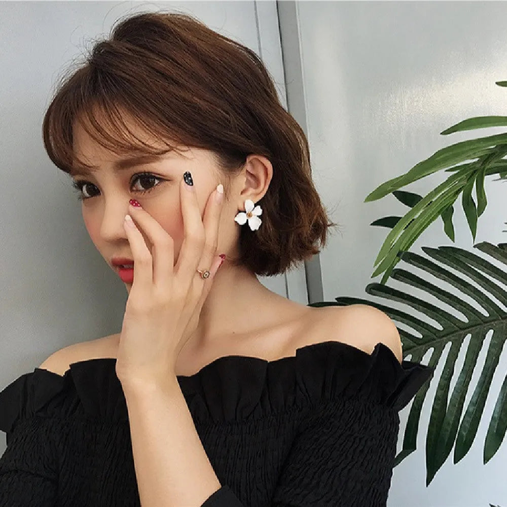 A pair of flower-shaped stud earrings for women in either pink or white alloy with an electroplated finish.