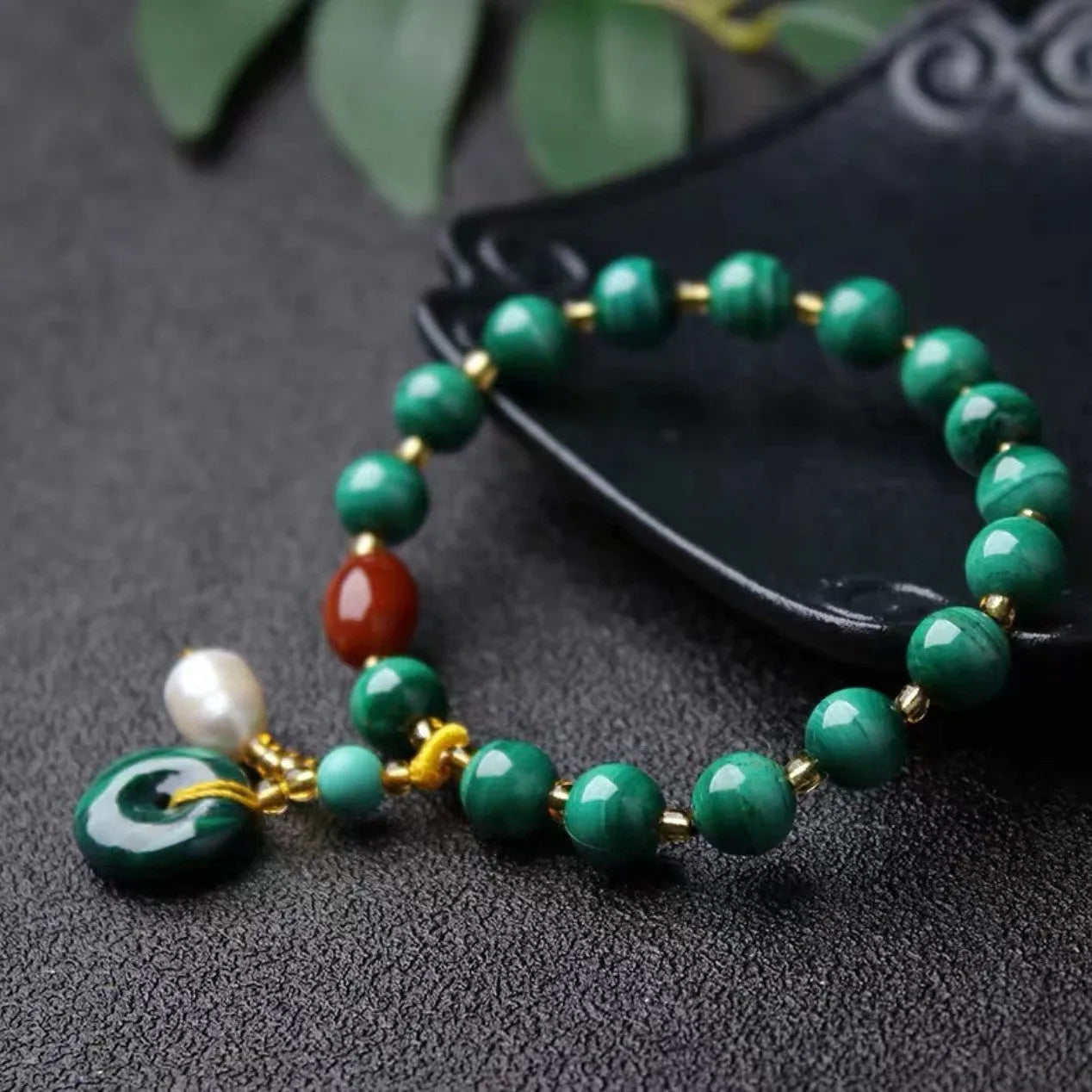 Handmade natural malachite and red agate barrel bead bracelet on a wrist, showing green and red stone details.