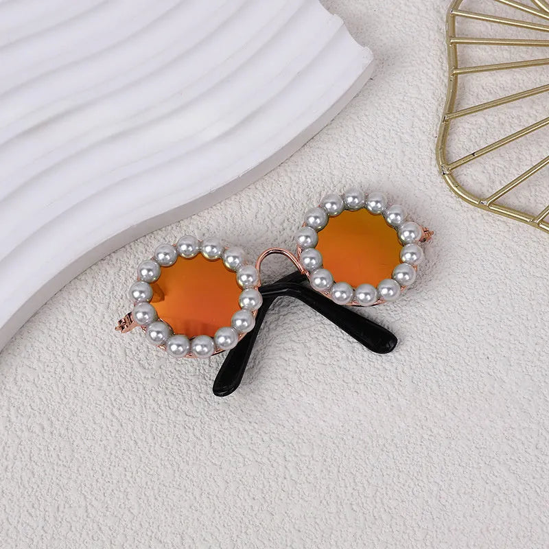 Cat wearing black pearl-rimmed round sunglasses as costume accessory for party
