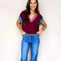 Burgundy loose-fitting women's V-neck sweater with light contrast trim on the neckline and cuffed short sleeves.