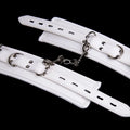 White PU sponge bondage ankle cuff and handcuff set with matching neck scarf on plain background