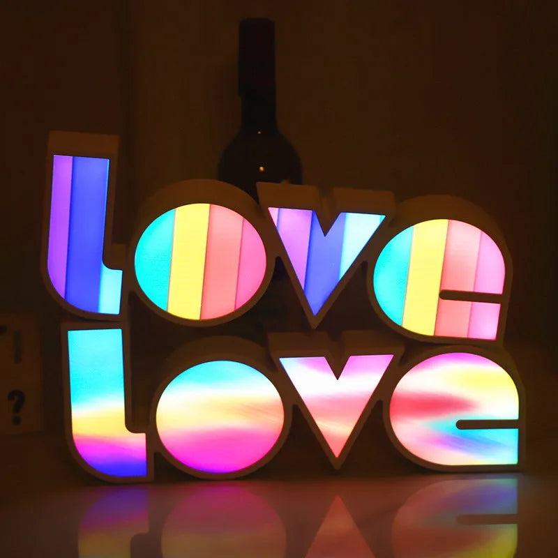 LED LOVE light with rainbow lampshade on a table against a dark background