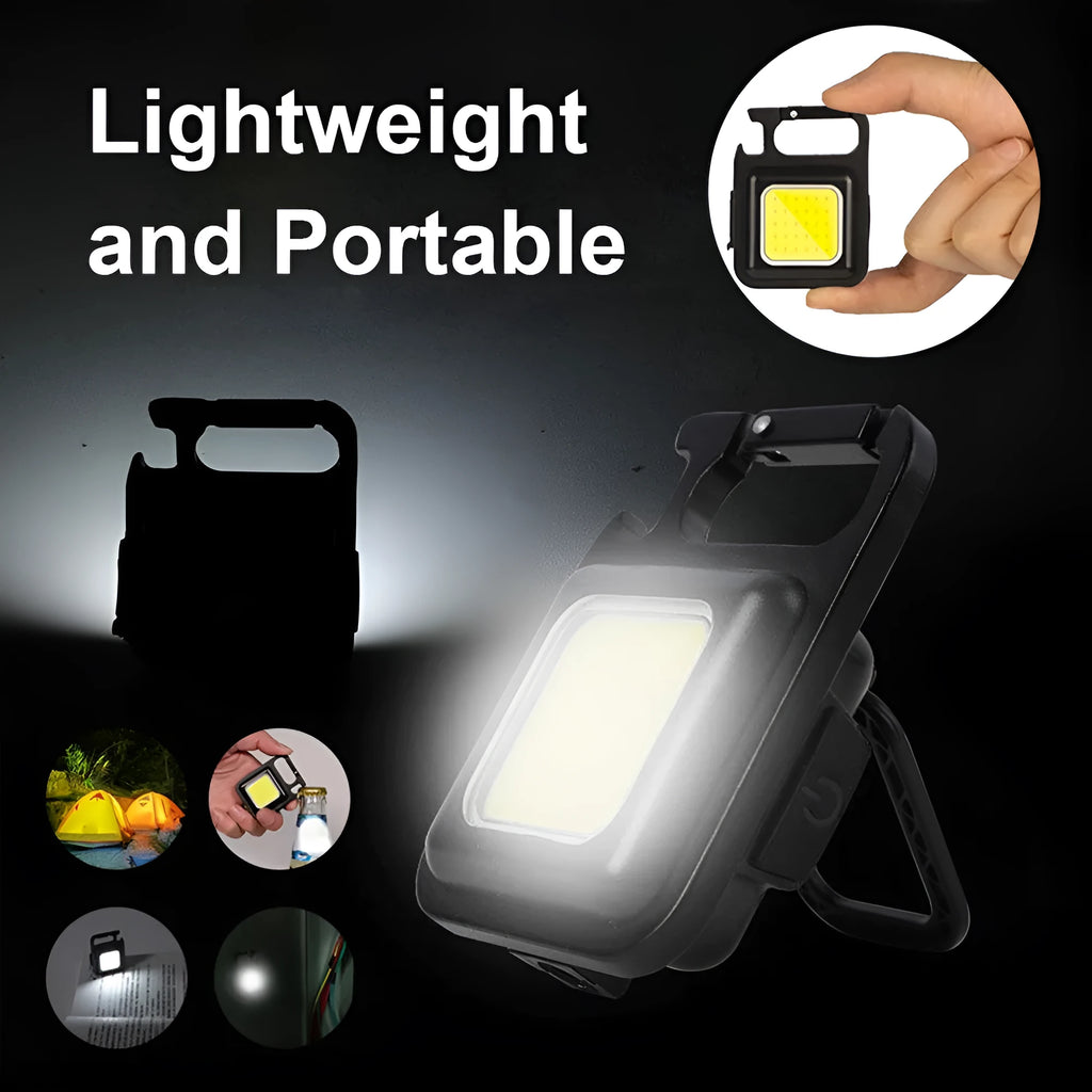 Black aluminium alloy COB keychain flashlight on a metal surface, magnetic base attached, 6x4.2cm size, with foldable handle extended
