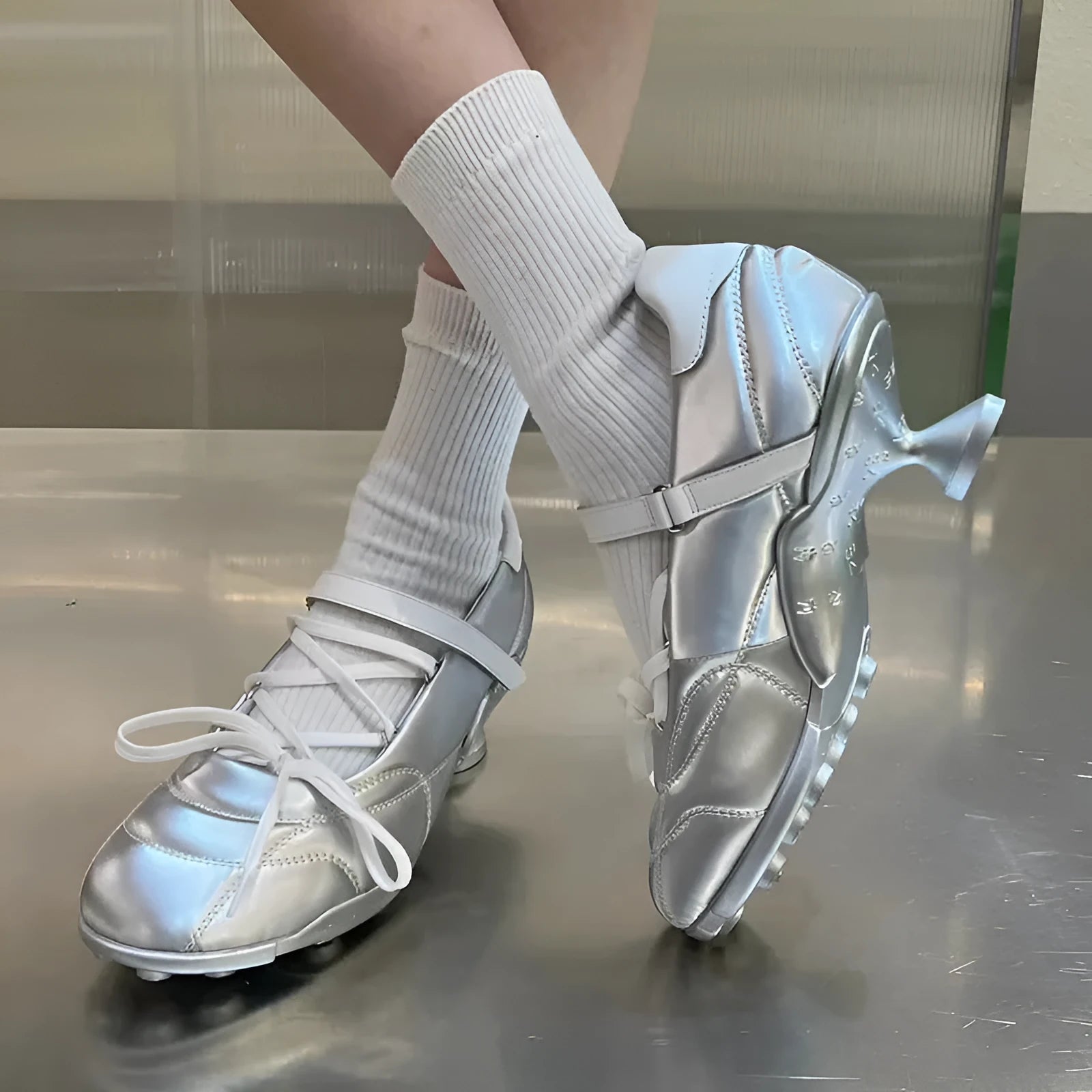 Women's silver low-top sports shoes with front lace-up, bow detail, and a mid heel on a white background.