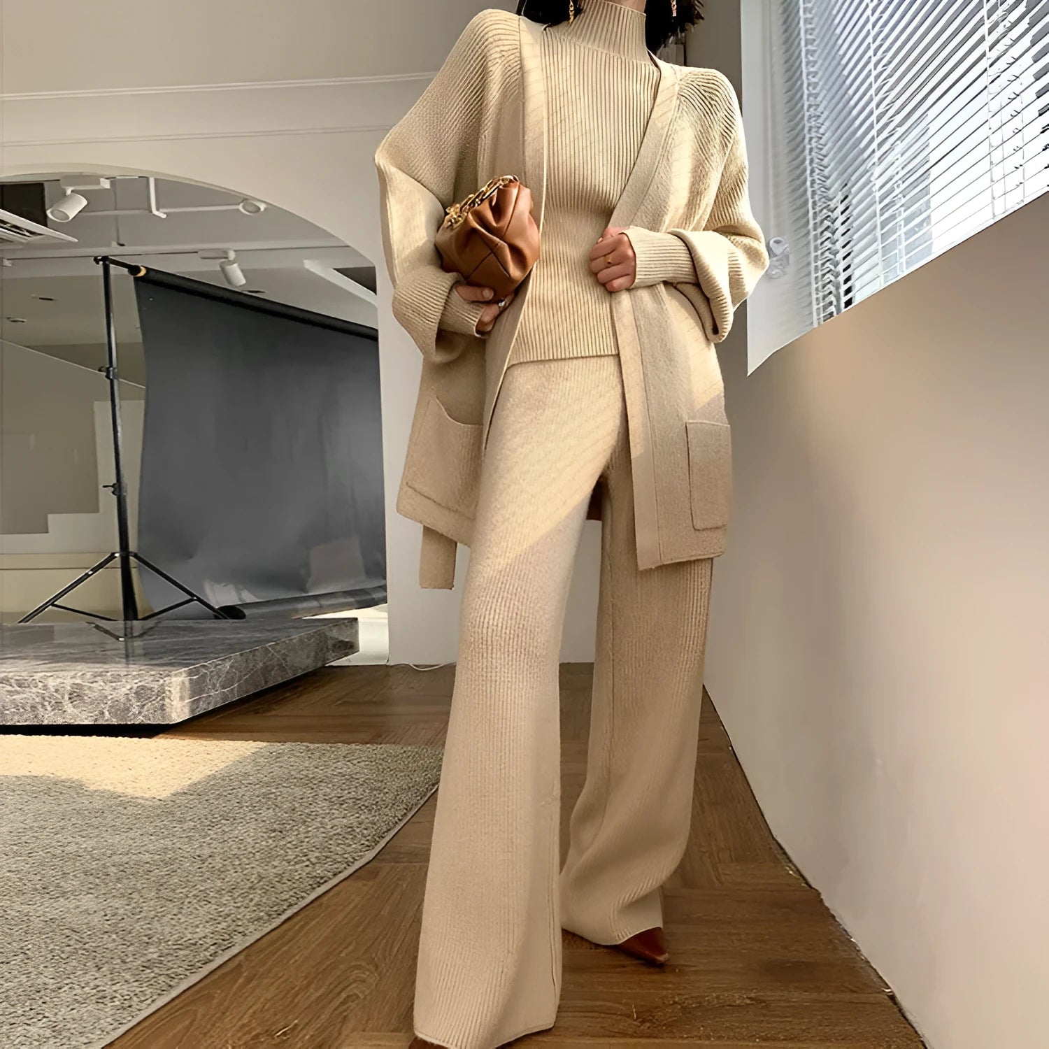 Women's knitted three-piece set showing wide-leg pants, sweater and cardigan with leather stitching details