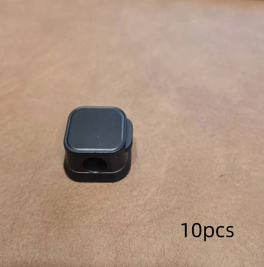 Magnetic cable clip in white holding a USB cable under a desk, with adhesive backing visible