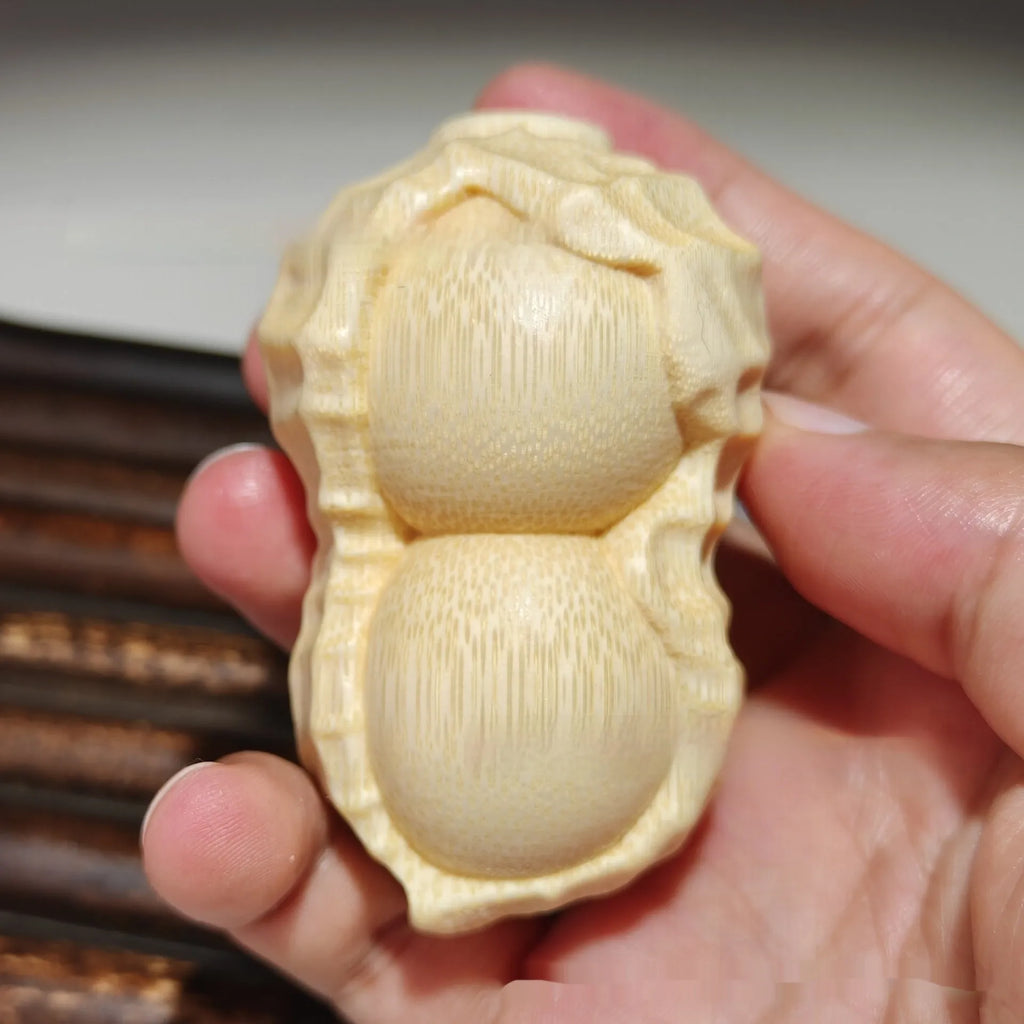 Solid natural bamboo ornament carved into a peanut shape on a wooden surface.
