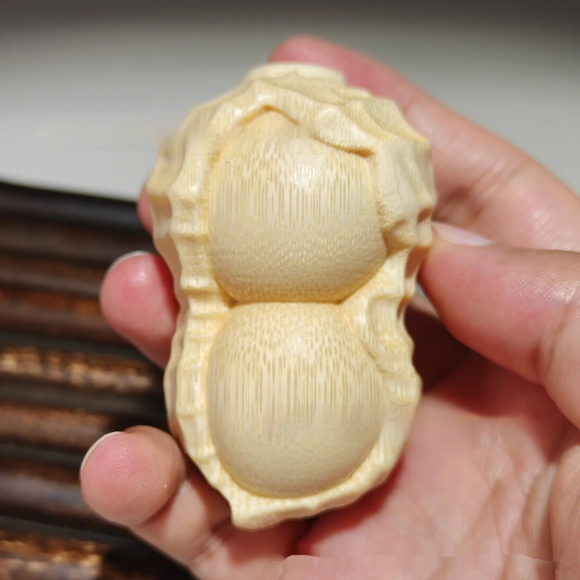 Solid natural bamboo ornament carved into a peanut shape on a wooden surface.