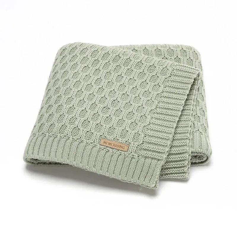 Solid colour acrylic baby blanket with textured lines, shown in a neutral shade, dimensions 70x90 cm
