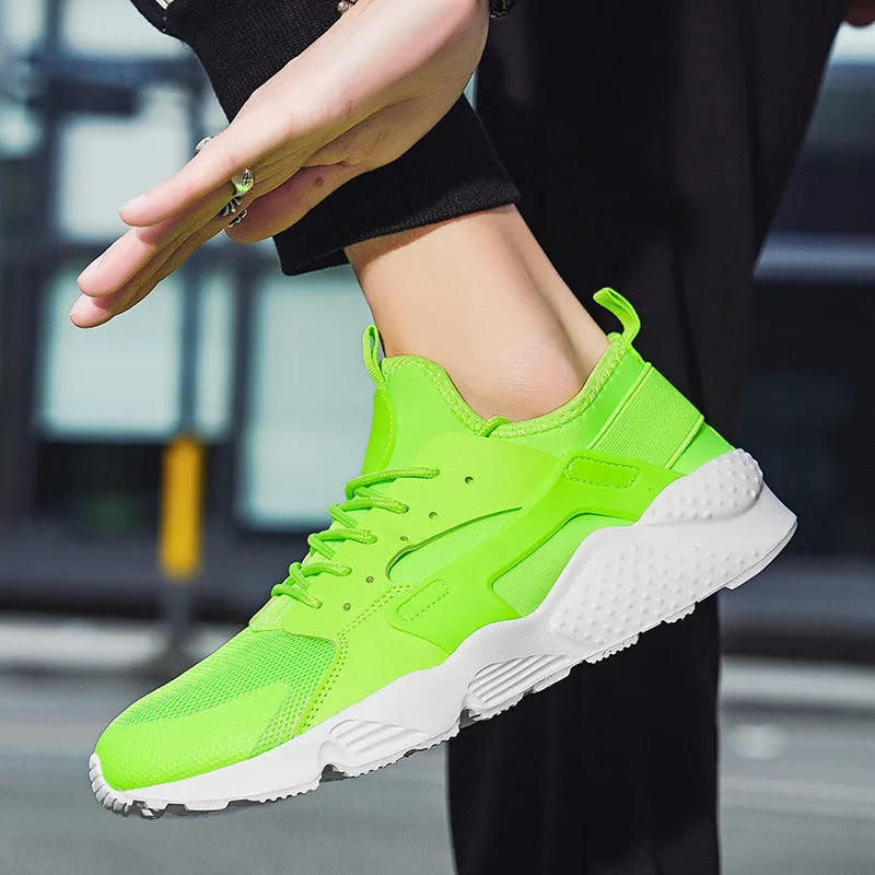 Men's green low top lace-up casual trainers with mesh upper and cross strap detail on a white background.