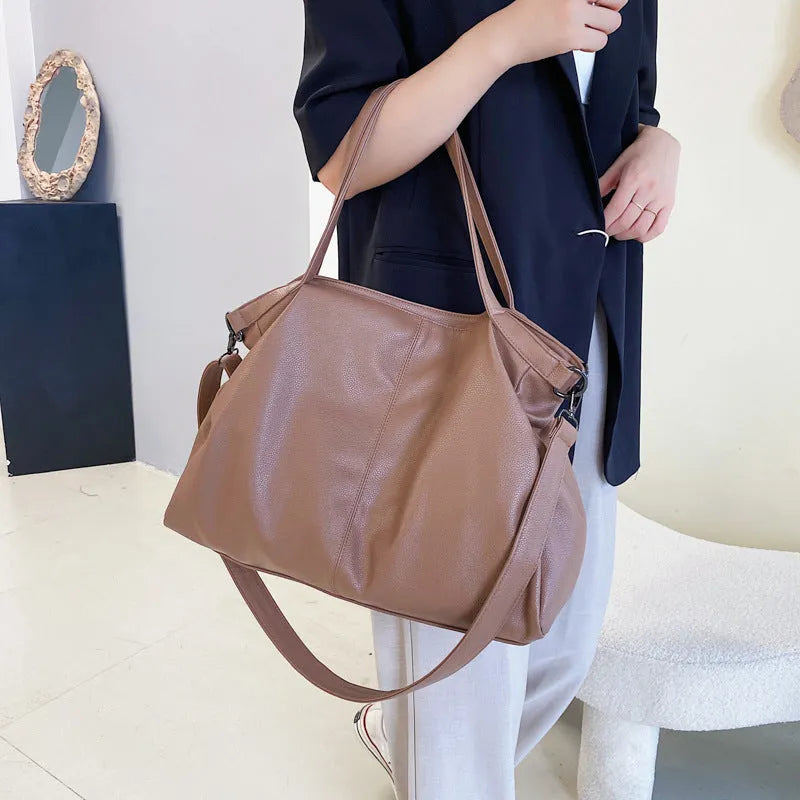 Large soft surface PU messenger bag in horizontal square shape with shoulder strap and top handle.