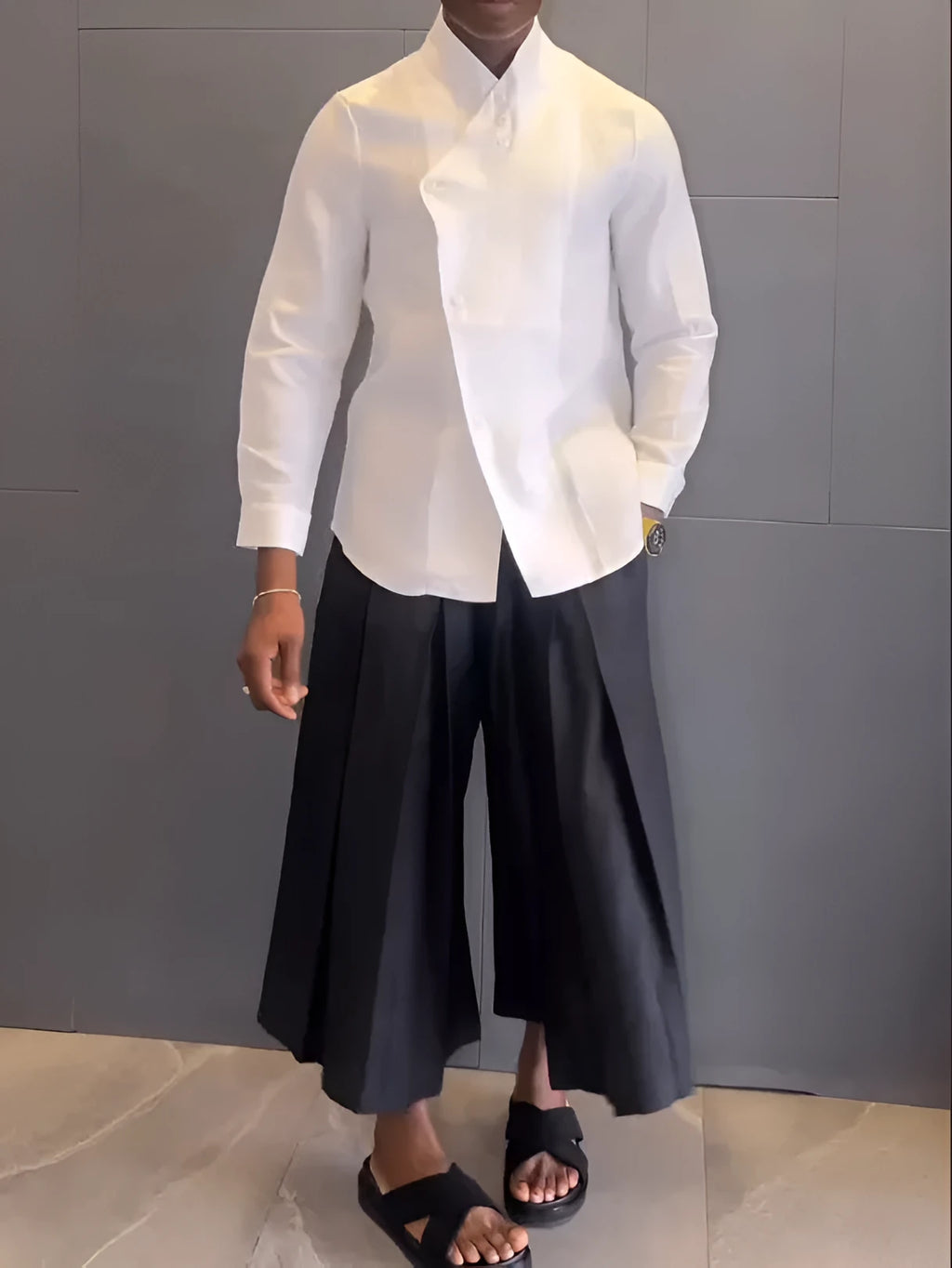 White asymmetric long sleeve shirt with black pleated pants set on a model for casual wear