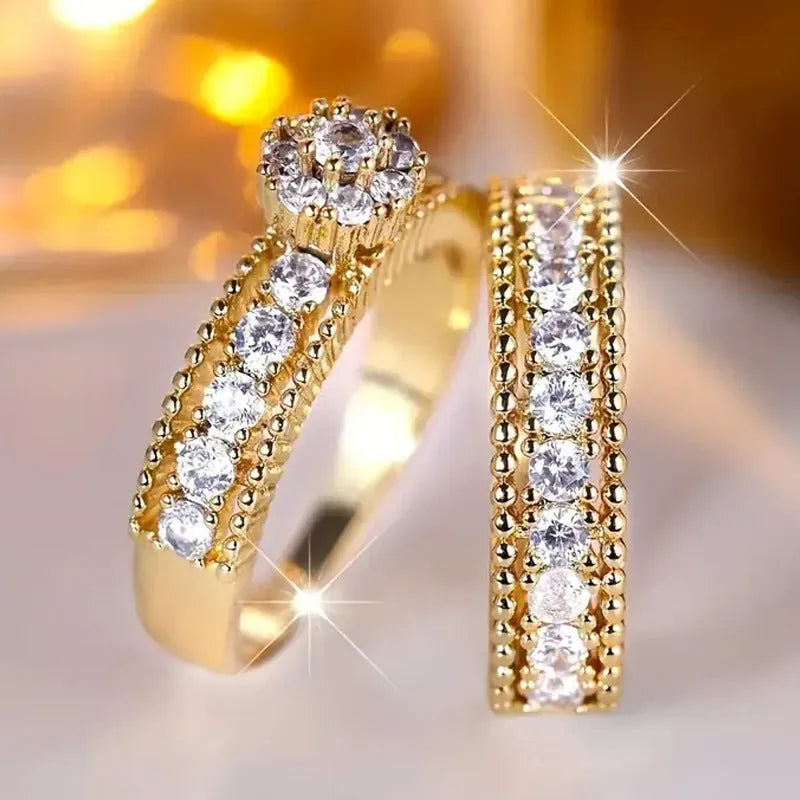 Two gold geometric zinc alloy rings with electroplated finish on white background