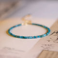 Natural blue apatite crystal bracelet with diamond-shaped beads, blue and grey colour, on a white background