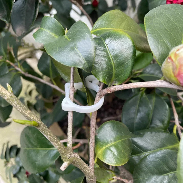 Red plastic plant clip in the shape of a cat, shown next to a small plant stem.