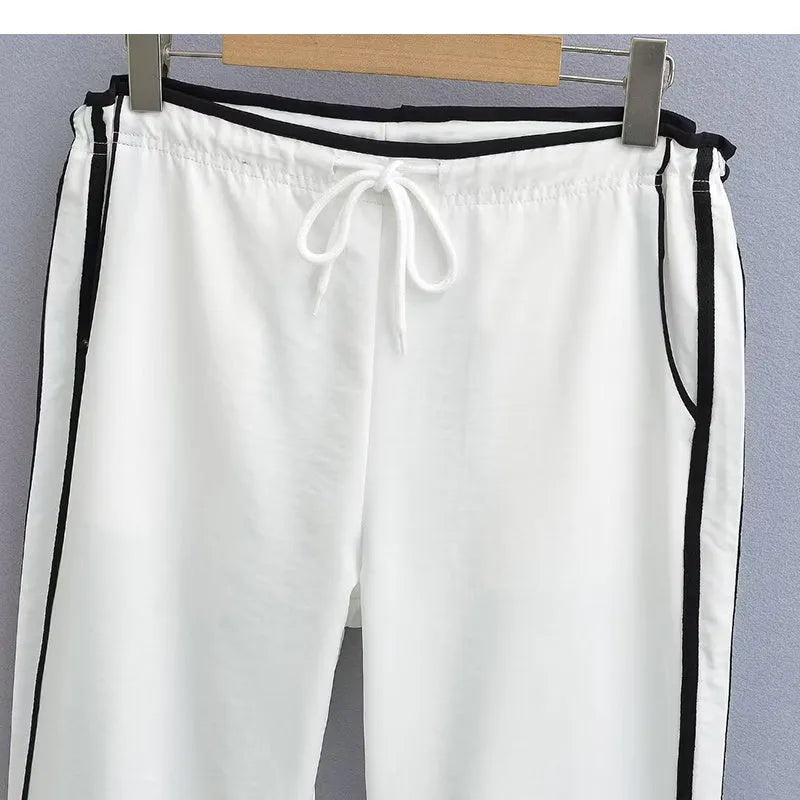 Navy blue loose straight-leg trousers with ribbon parallel bars contrast detail on a hanger.