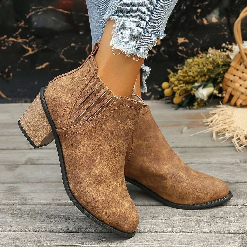 Black women's pointed toe ankle boots with a thick square low heel and slip-on design.