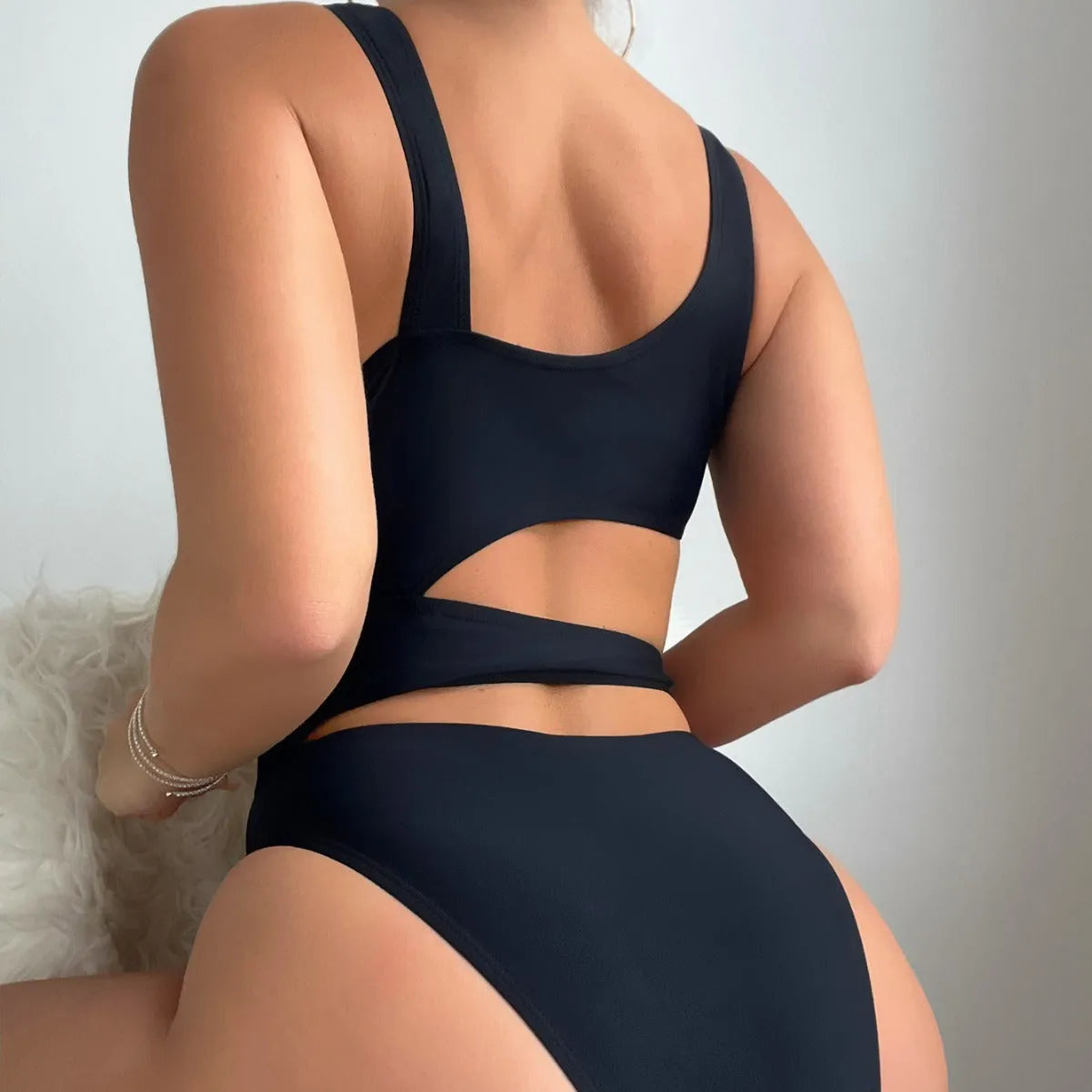 Women's solid black one-piece swimsuit with hollow cut-out design and high-cut leg on display