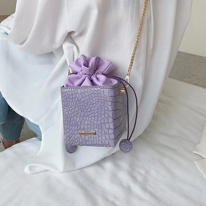 Small women's messenger bag with chain strap in six colour options showing bucket shape and zip opening