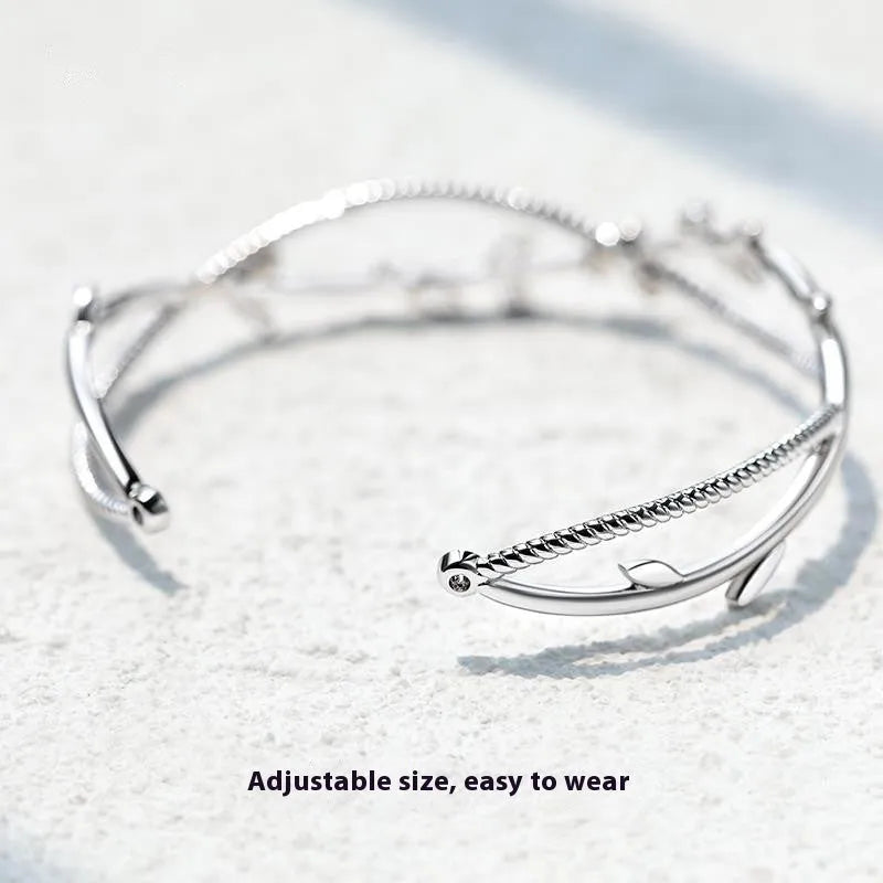 Cross twisted branch sprout bracelet in electroplated white gold Z4136 on a natural background