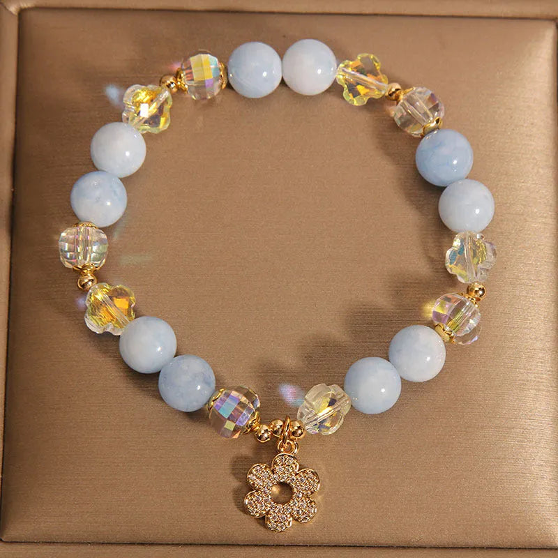 Women's aquamarine crystal bracelet with four-leaf clover design and pearl accents on a wrist.
