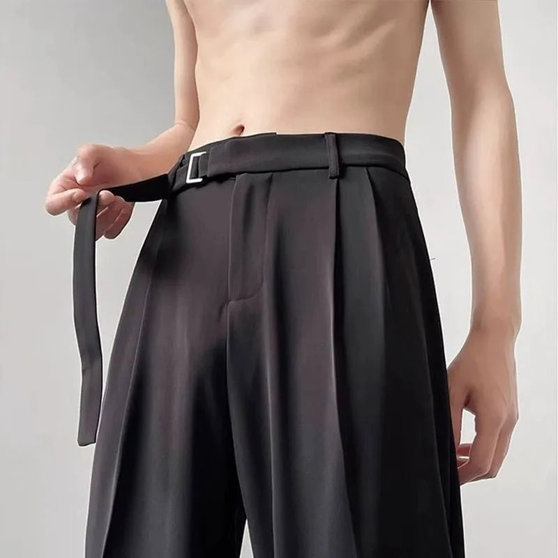 A pair of thin, straight-cut wide leg trousers in black on a hanger.