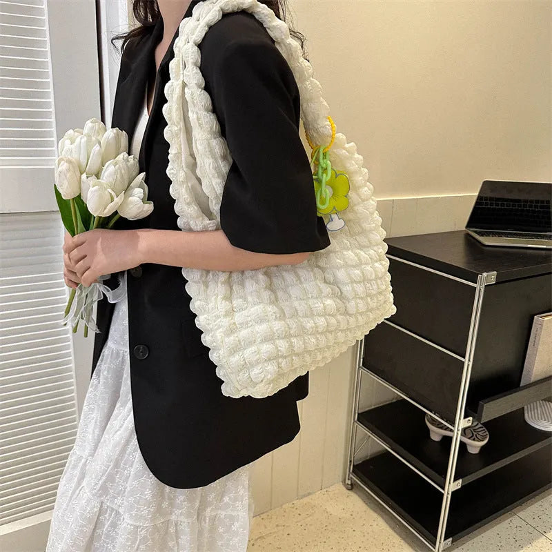 Pleated bubble bag in beige polyester with fold detailing, pendant, and cross-body strap