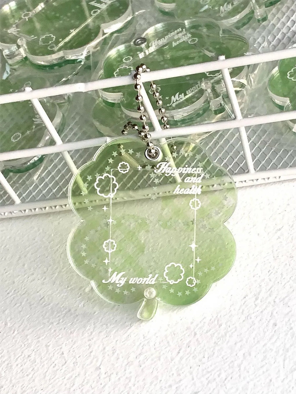 Four-leaf clover shaped acrylic pendant keychain in mint green colour on a surface