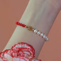 Women's pearl braided red rope bracelet with domestic 14K gold plated fu character charm on red background