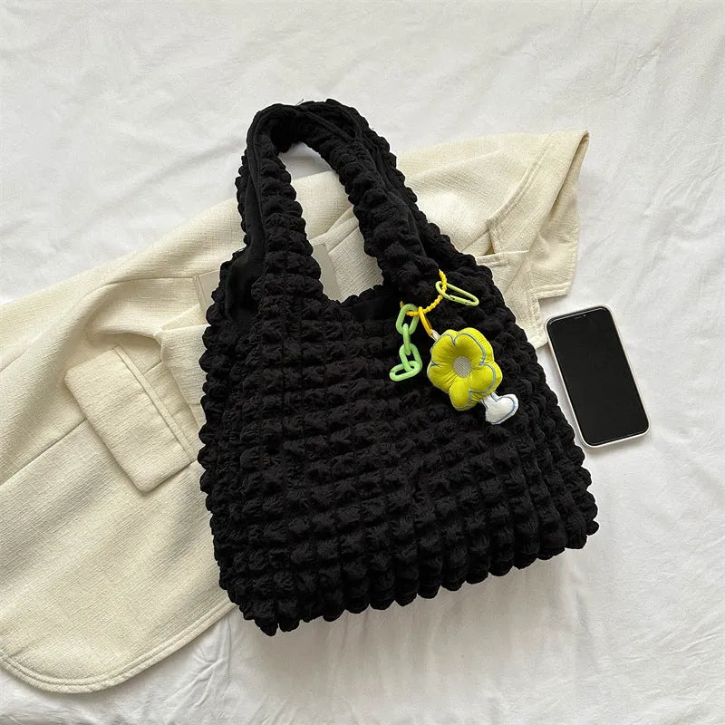 Pleated bubble bag in beige polyester with fold detailing, pendant, and cross-body strap