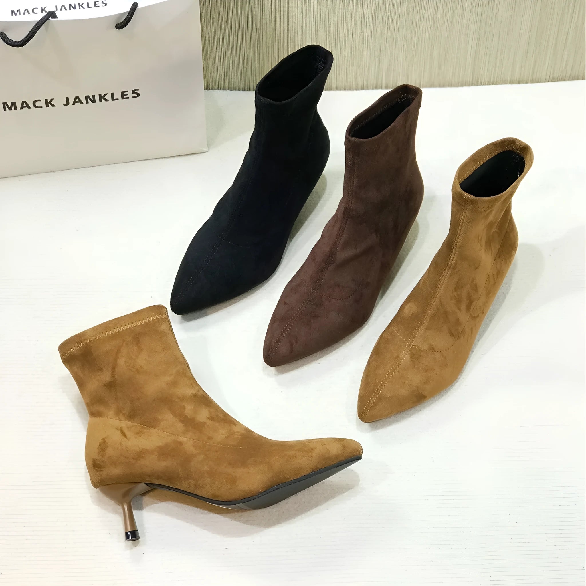 Black pointed toe ankle boots with a stiletto heel on a white background