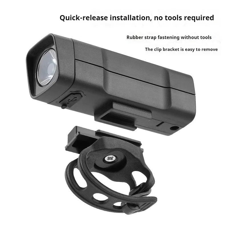 Black bicycle headlight with LED lens mounted on handlebars via a quick-release strap bracket.