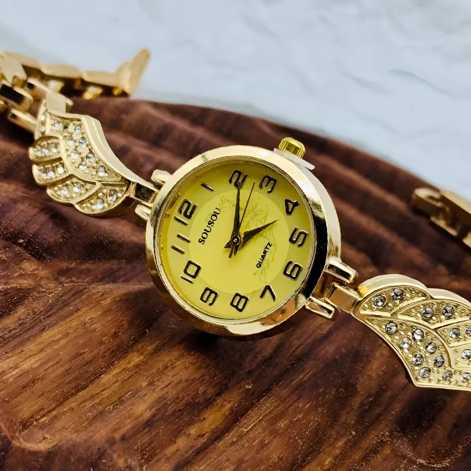 Women's stainless steel watch with round dial on wrist, showing gold surface colour option.