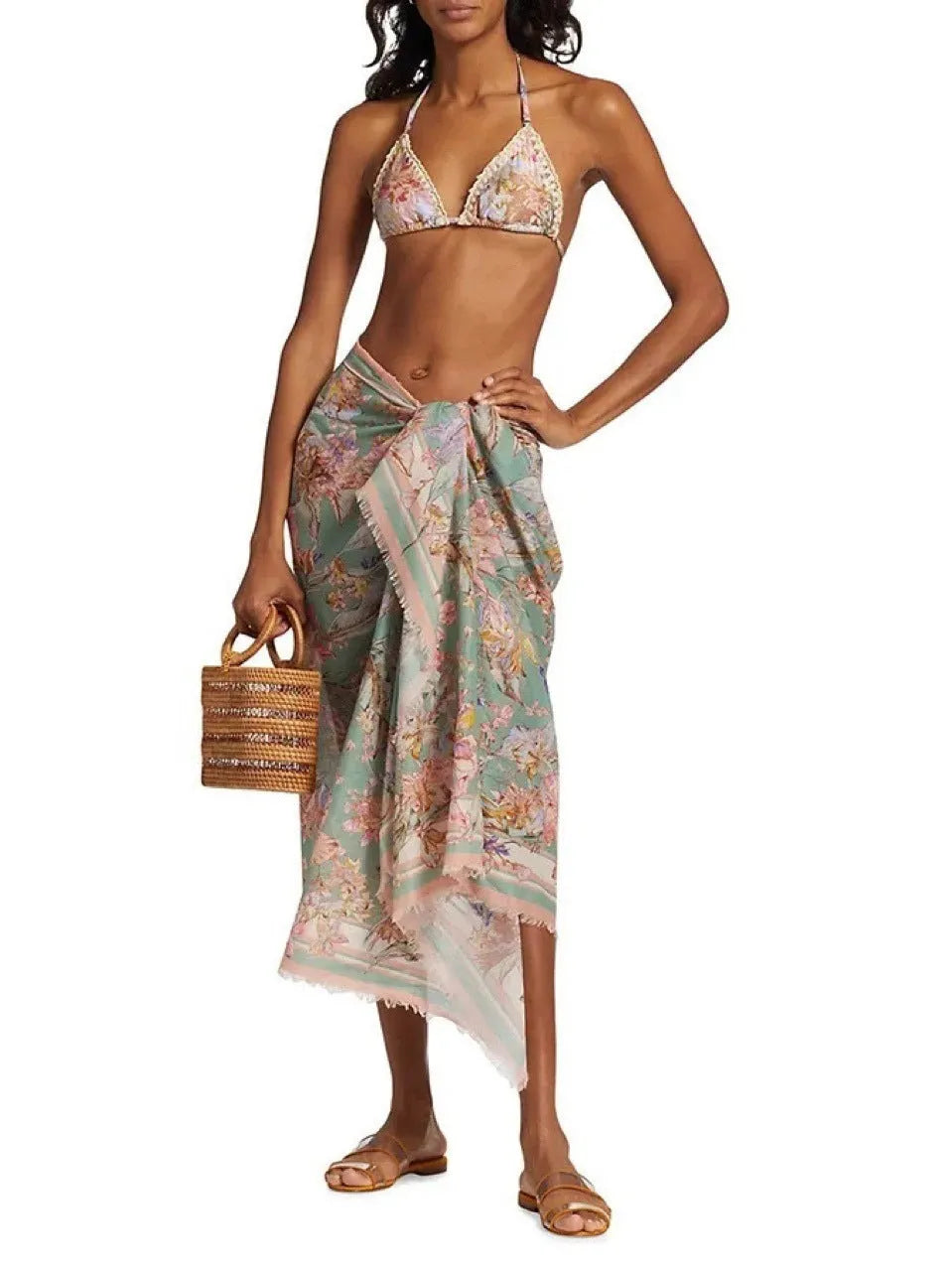 Creamy-white floral print women's three-piece bikini set with top, briefs, and skirt on a beach background.