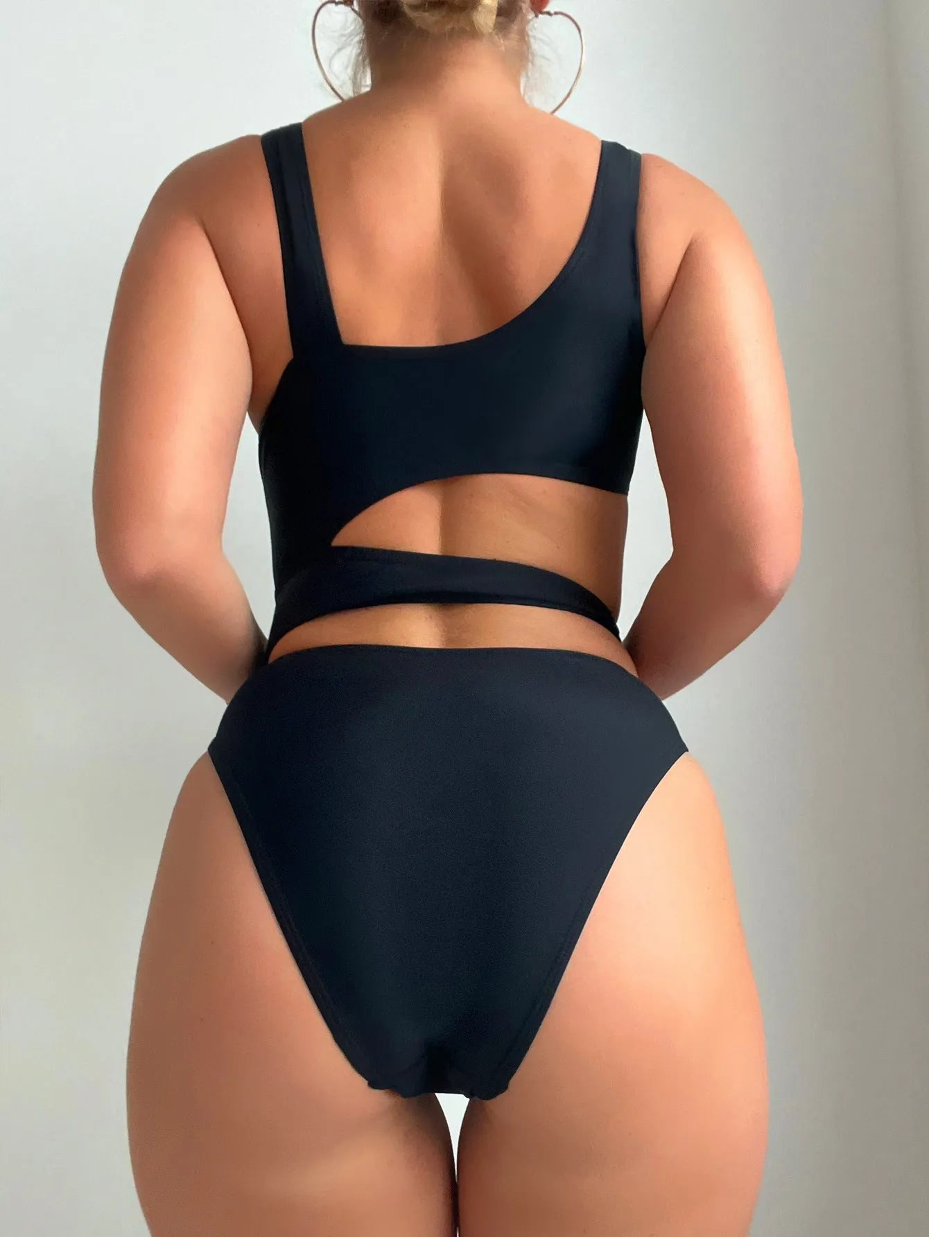 Women's solid black one-piece swimsuit with hollow cut-out design and high-cut leg on display
