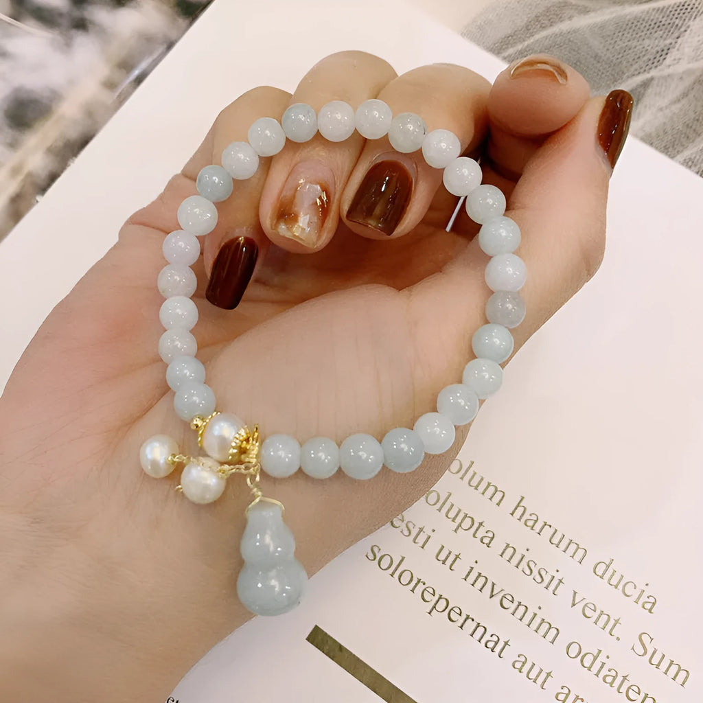 Close-up of a Chinese style jade bracelet for women featuring a natural emerald jade gourd charm on a band.