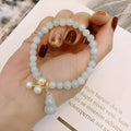Close-up of a Chinese style jade bracelet for women featuring a natural emerald jade gourd charm on a band.