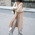 Long grey knitted cardigan coat with a hood and regular sleeves on a model.