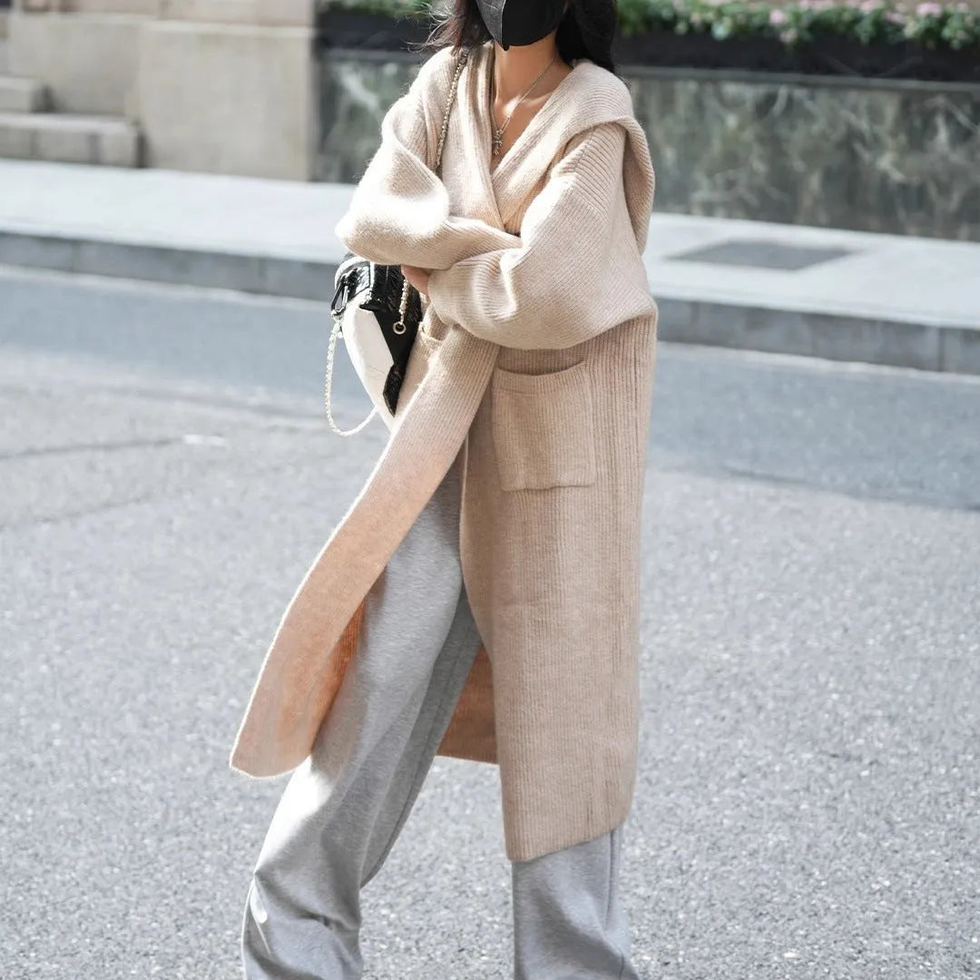 Long grey knitted cardigan coat with a hood and regular sleeves on a model.