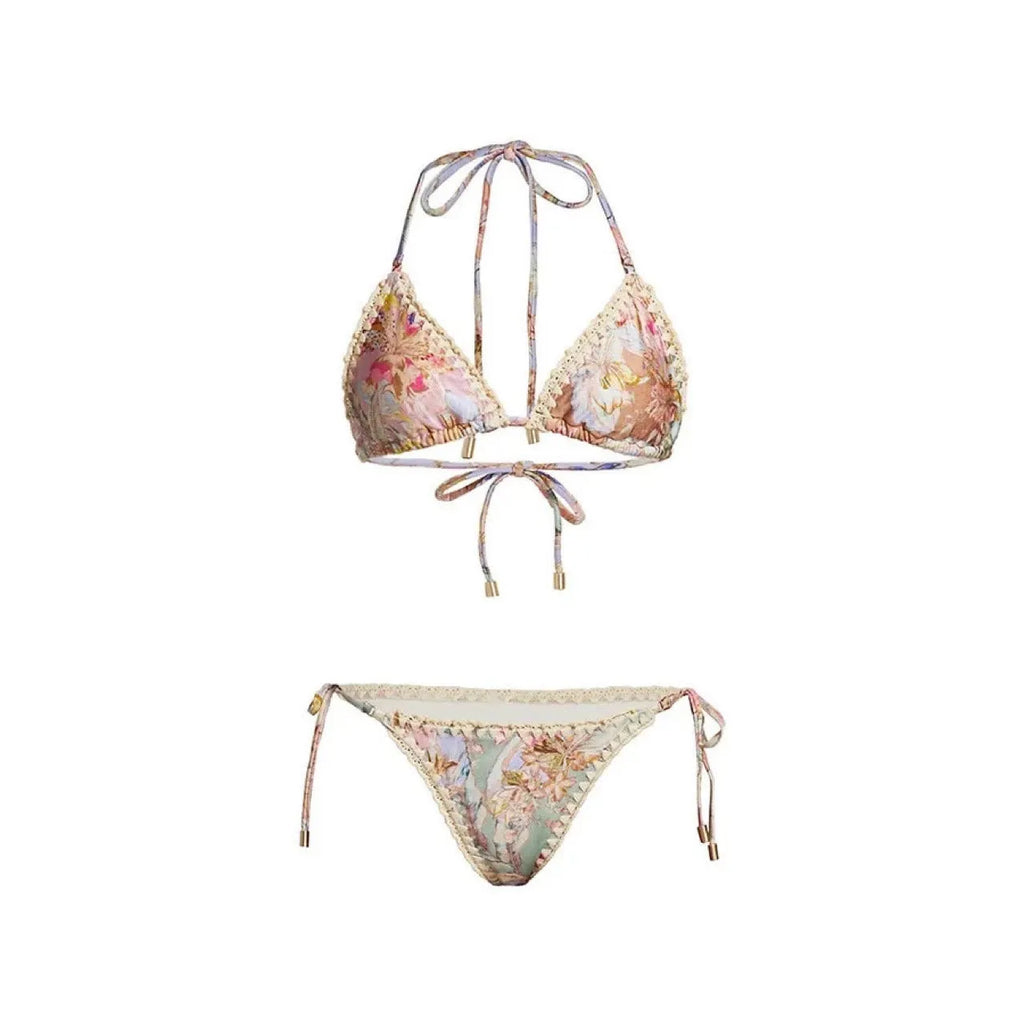Creamy-white floral print women's three-piece bikini set with top, briefs, and skirt on a beach background.