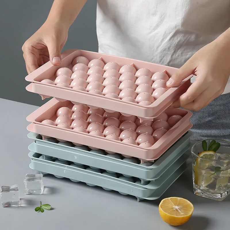 Round ball ice cube tray in sky blue with 33 grids, empty and filled with water, on a kitchen countertop