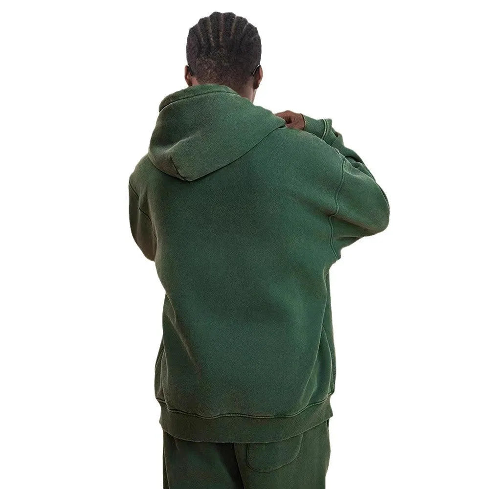 Man wearing a vintage washed dark green hooded cardigan with a double zipper and fleece lining.