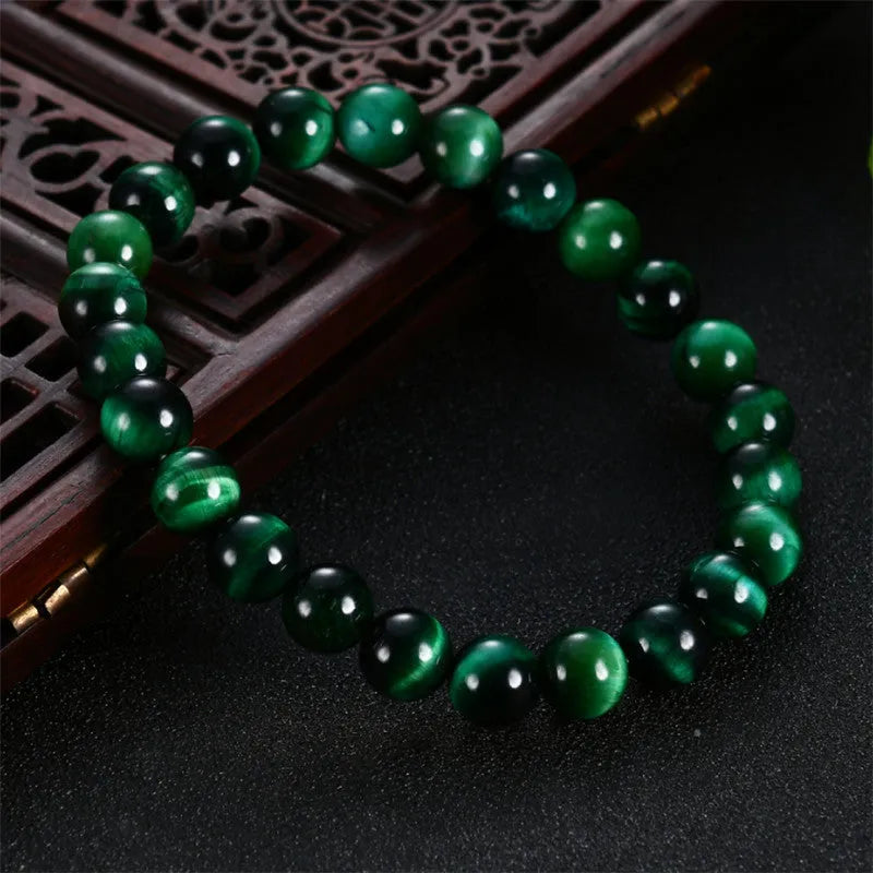 Green polished Tiger Eye stone bracelet with geometry beads, shown on a wrist.