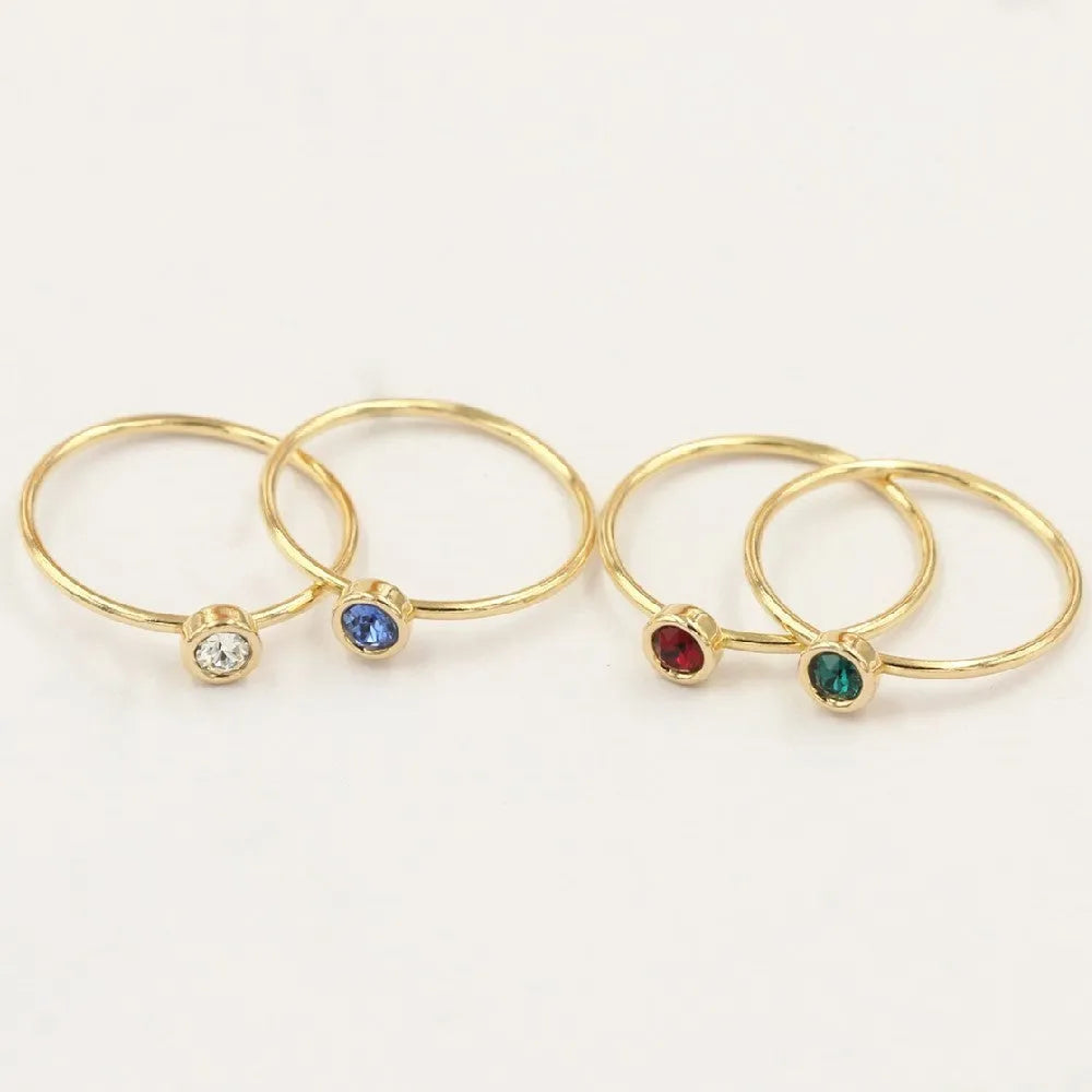 Gold-plated women's knuckle ring with clear stones in green, blue, red, or white on a copper band.
