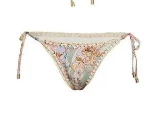 Creamy-white floral print women's three-piece bikini set with top, briefs, and skirt on a beach background.
