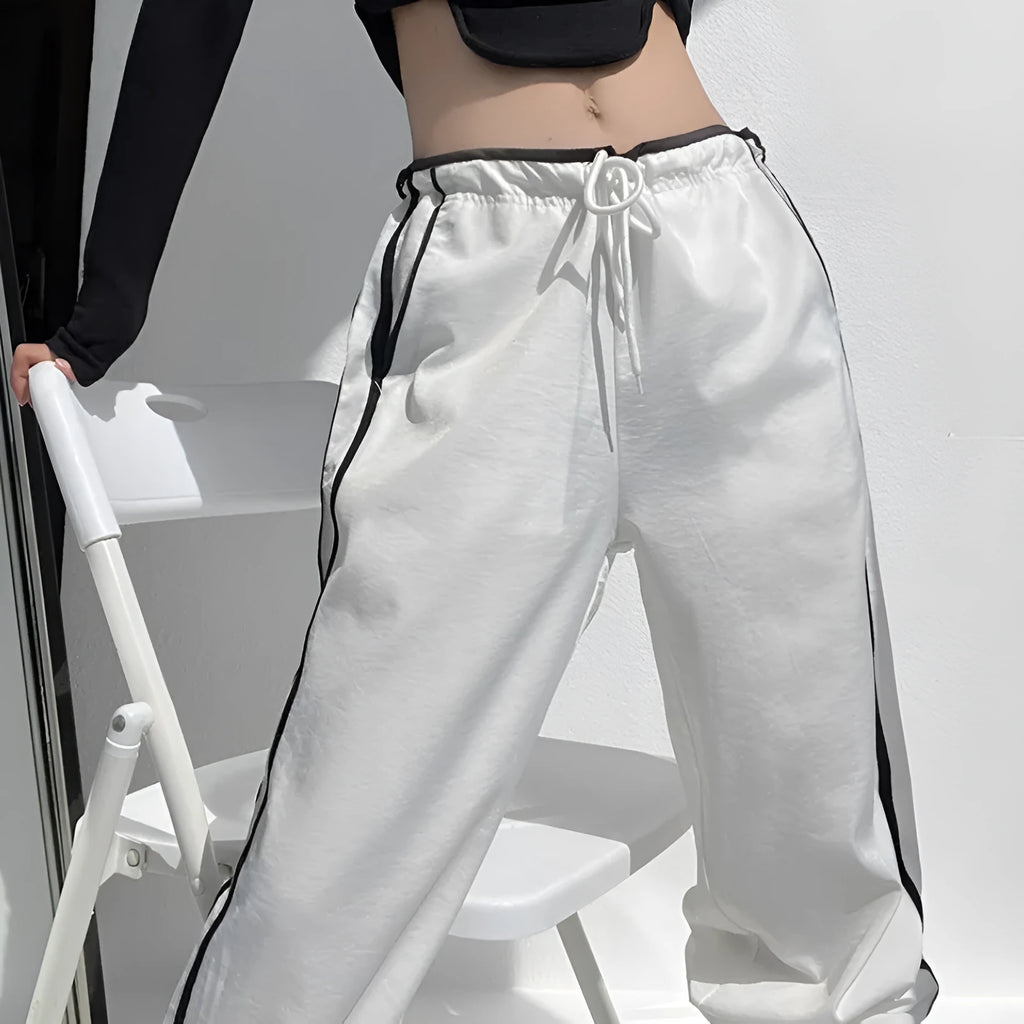 Navy blue loose straight-leg trousers with ribbon parallel bars contrast detail on a hanger.